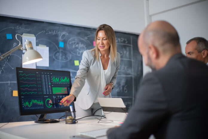 Company employees discussing market data on charts