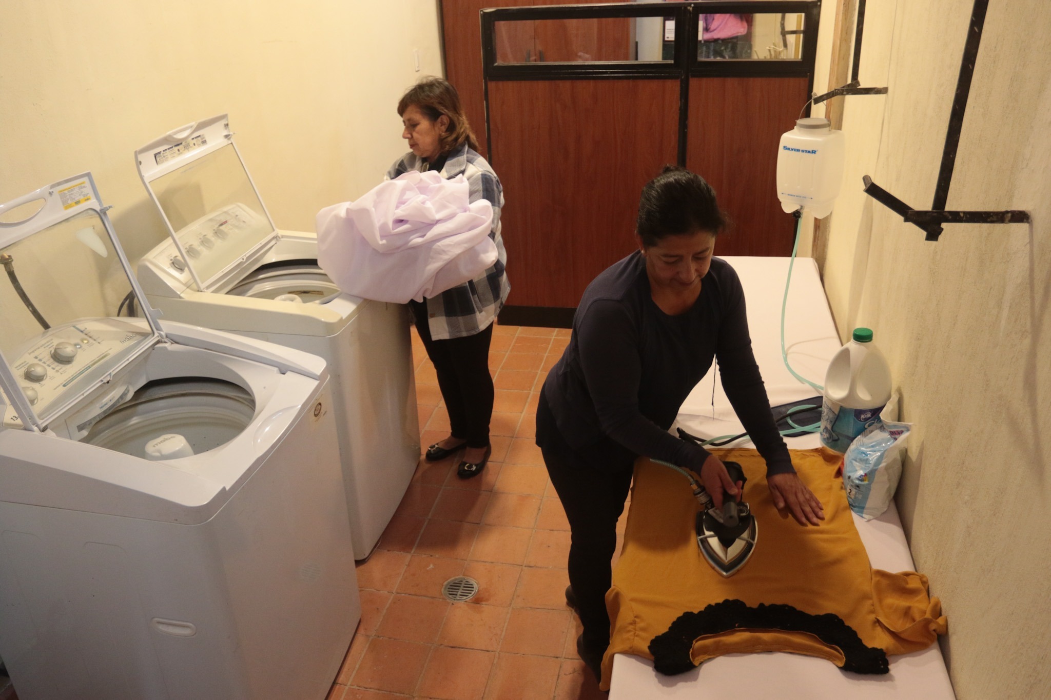 Janeth León y Digna Barros prueban las lavadoras y el área de planchado que se implementó en la Casa de la Mujer. XCA